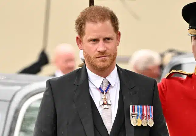 Why is Prince Harry not in a regal robe or military uniform at the coronation?