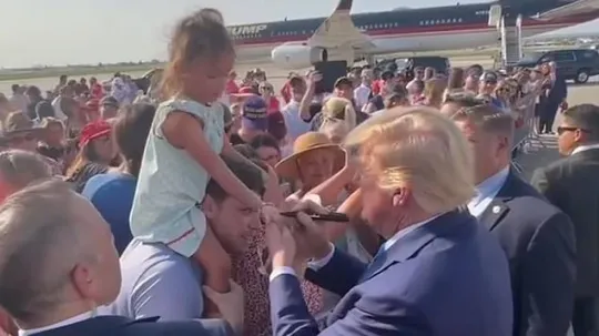 Young daughter watches in confusion as Trump signs her hand with permanent marker